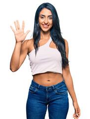 Fototapeta premium Beautiful hispanic woman wearing casual clothes showing and pointing up with fingers number five while smiling confident and happy.
