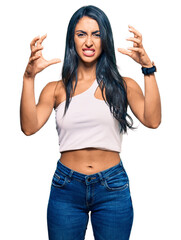 Beautiful hispanic woman wearing casual clothes shouting frustrated with rage, hands trying to strangle, yelling mad