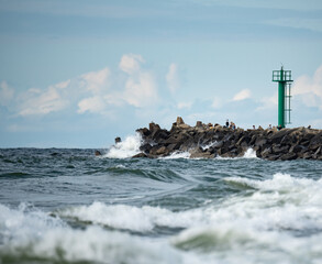 A storm in the Baltic Sea. Rough sea in the background a concrete breakwater with a lighthouse....