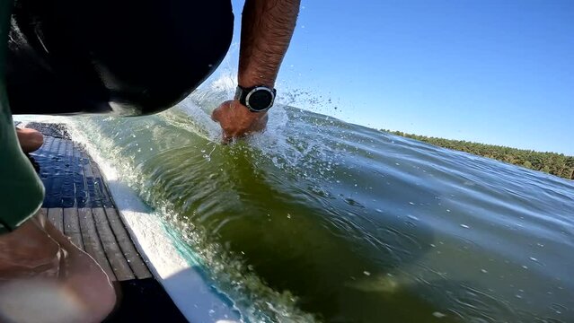 surfer with hand in wave on longboard surfing waves