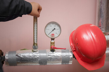 Professional plumber servicing the heating system in the boiler room and writing on a clipboard