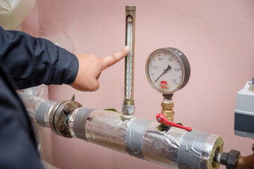 Professional plumber servicing the heating system in the boiler room and writing on a clipboard