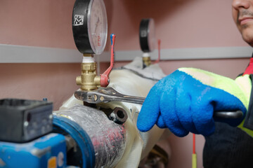 Plumber technician works with water pressure meter in boiler room