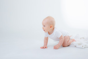 baby boy in a white bodysuit crawling on a white background