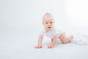 baby boy in a white bodysuit crawling on a white background