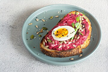 Whole grain toast with beetroot hummus, seeds, egg and microgreens (sprouted pea sprouts) on a...