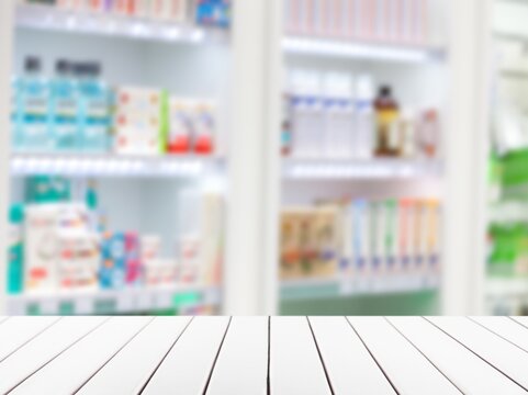 Empty White Counter Top With Blur Pharmacy Drugstore Shelves Background