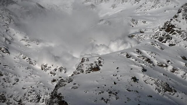 A large avalanche Made with power goes down a rocky Swiss alps Mountain next to ski slopes, science