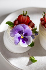 Sweet pavlova's dessert decorated with fresh strawberry and flowers