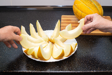 People take sliced ripe juicy melon slices from the plate with their hands. Delicious healthy food