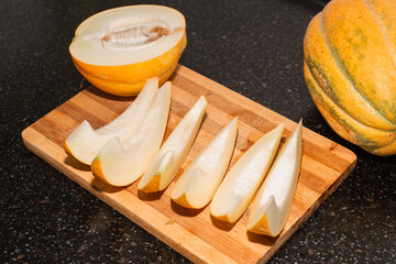 Ripe juicy melon cut into slices on a wooden board. Delicious healthy food