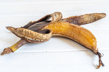 Rotten banana on white wooden background.