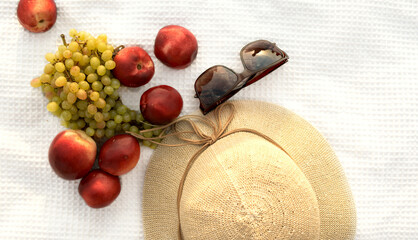 summer hat, sunglasses, peaches and grapes on a white background