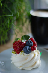 Dessert Pavlova - close-up. Morning breakfast in a cafe with a delicate dessert with cheese cream and fresh berries.