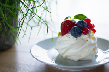 Dessert Pavlova - close-up. Morning breakfast in a cafe with a delicate dessert with cheese cream and fresh berries.