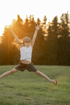 Mädchen, 8 Jahre, springt bei Sonnenuntergang auf einer Wiese