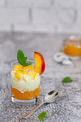 Peach fruit dessert in a glass cup with curd cream and peach jam.