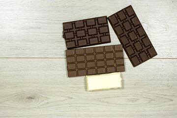 milk and black, white chocolate bars on wood table