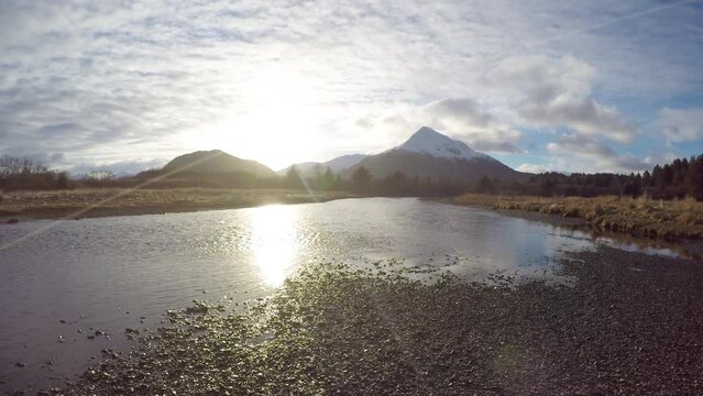 A time lapse of the setting sun and moving clouds over the mountains and a salmon river on Kodiak Island Alaska