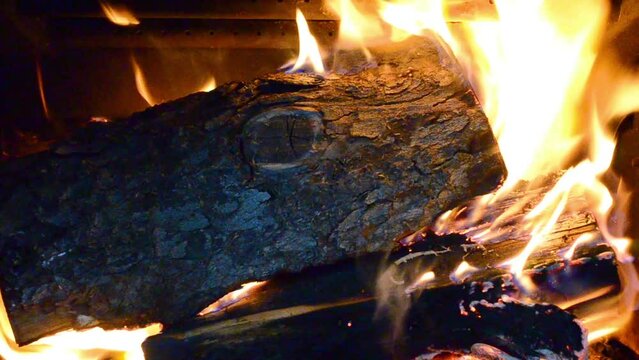 A closeup shot of a burning log in a woodburning stove fireplace