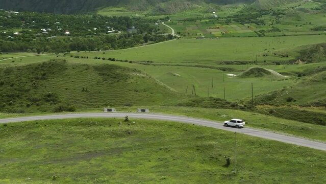 SUV Car Driving On The Road Through Rural Landscape Near Aspindza In Georgia. aerial drone pullback