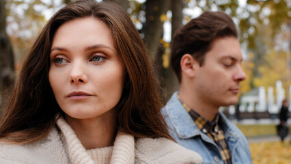 Caucasian girl offended by male lover on background young family couple standing outdoors ignoring each other looking different ways conflict misunderstanding sad woman thinking breakup with boyfriend