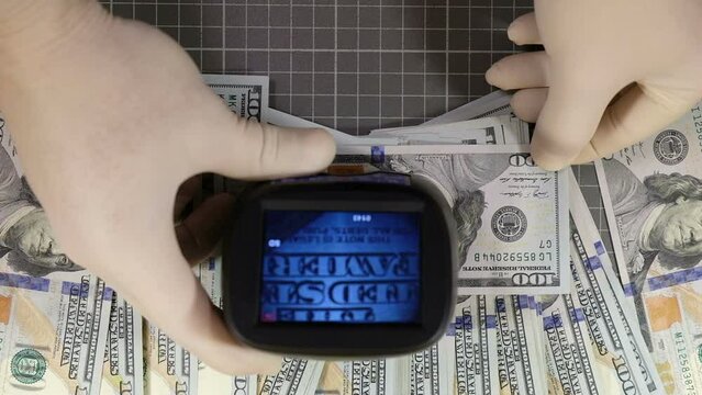 Checking the authenticity of dollars with a currency detector close-up, forensic examination of banknotes