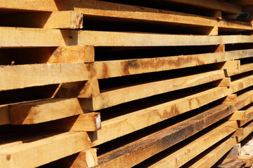 Wooden boards close up. Lots of boards stacked on top of each other in a warehouse. Perspective angle of wooden boards close-up in a lumber warehouse. Background from boards.