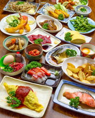 居酒屋や和食レストランで提供される、刺身、天ぷら、出し巻き卵、焼き魚など彩り豊かな一品料理の数々。テーブルいっぱいに並べられた豪華でボリューム満点な宴会メニューの俯瞰写真