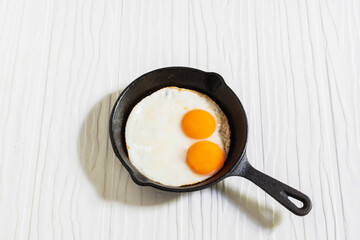 Healthy breakfast food fried egg in skillet pan on white wood table.