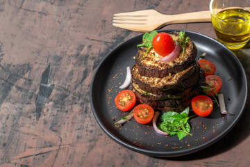 Grilled eggplants in black plate on wood background.