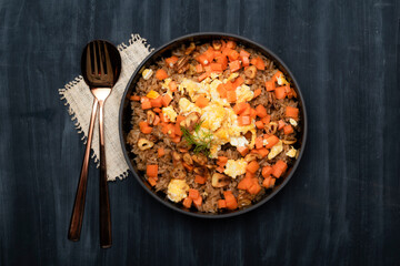 Healthy food garlic fried rice with egg carrot in black bowl on background.