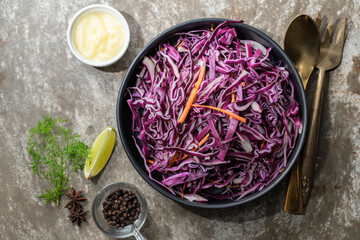 Healthy purple cabbage salad in black bowl on loft background.
