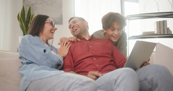 Happy family watches video on laptop talking and smiling