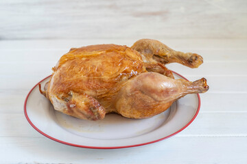 Whole roasted chicken on ceramic plate.