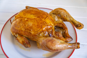 Whole roasted chicken on ceramic plate.