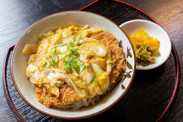 カツ丼 卵とじ とんかつ 豚カツ 玉子 どんぶり 玉ねぎ かまぼこ 刻みねぎ 漬物 揚げ物 豚肉料理 和食 日本食 ランチ 昼食 定食 飲食店 メニュー 広告素材 | Japanese Katsudon Pork Cutlet Rice Bowl Simmered Egg and Fried Pork with Pickles Close-up Table View