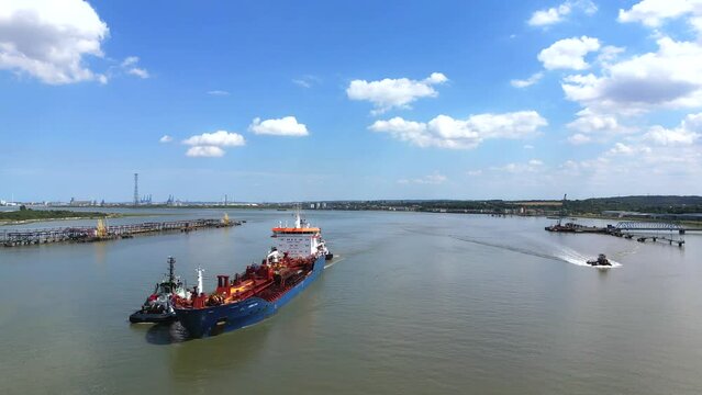 Shipping, bulk carrier sailing up the Thames river, London. Guided by two tugs.
