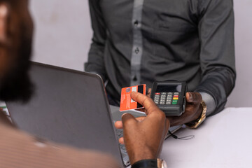 nigerian businessman using a point of sale device with a client