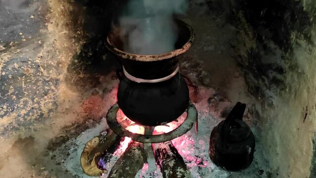 Moroccan couscous cooking on a couscoussier steamer (called a kiskis ) to steam it
on a wooden fire in a fireplace, smoke and flame surround the pot. Traditional plate. Morocco.