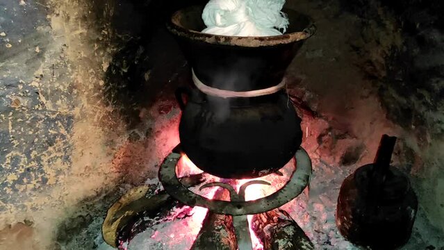 Moroccan couscous cooking on a couscoussier steamer (called a kiskis ) to steam it
on a wooden fire in a fireplace, smoke and flame surround the pot. Traditional plate. Morocco.