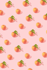 Trendy fruits pattern made with fresh peaches with and without leaves on bright pink background. Minimal healthy vegan organic food concept. Sunlit shadows and pastel colors.