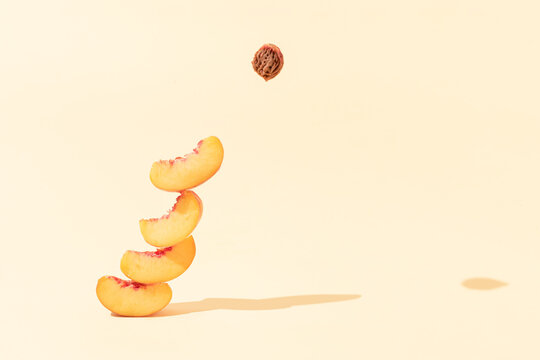 Authentic fruits composition made of peach slices and pit with sunlit shadows against bright beige background. Surreal creative food concept.