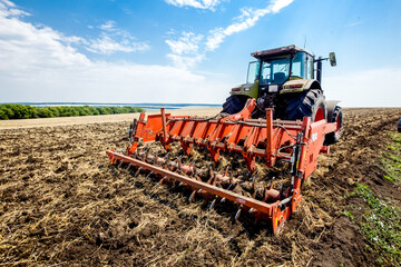 Fototapeta premium Tractor working in wheat field. Agriculture background. Harvest season