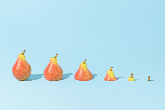 Fresh pears in descending size order, sinking in bright blue background. Creative food concept. Summer or autumn healthy fruits composition.