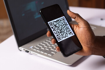 a black businessman holding a smartphone with a QR code on the screen