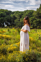 A young pregnant woman in a field touching her pregnancy belly