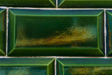 Background of old green tiles with cracks and iridescent tints