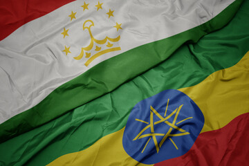 waving colorful flag of ethiopia and national flag of tajikistan.