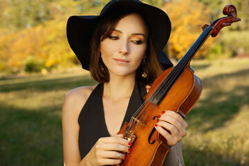 girl violinist in a black hat. bright autumn colors